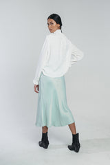 Neva blouse in white paired with kajo slip skirt in misty green. Picture from behind. Hálo from north